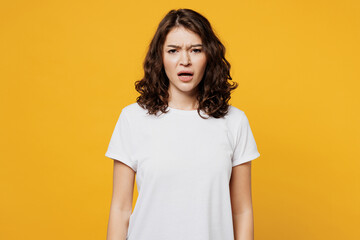 Young sad displeased dissatisfied indignant Caucasian woman she wearing white blank t-shirt casual clothes looking camera isolated on plain yellow orange background studio portrait. Lifestyle concept.