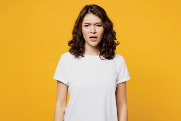 Foto op Plexiglas Young sad displeased dissatisfied indignant Caucasian woman she wearing white blank t-shirt casual clothes looking camera isolated on plain yellow orange background studio portrait. Lifestyle concept. © ViDi Studio
