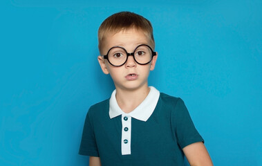 Photo of smiling happy boy highlighted on simple background. Back to school. Funny kid with glasses...