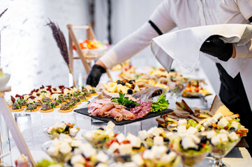 hands of a waiter prepare food for a buffet table in a restaurant