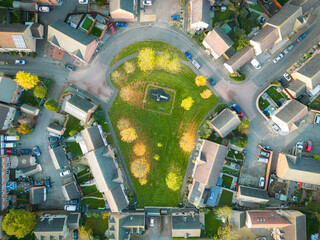 Drone top down view of a green space seen in late autumn in the UK. Autumn trees and kids play...
