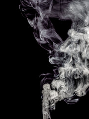 A jet of white smoke rises, streams and forms tubers isolated on a black background