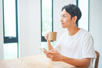 自宅のリビングでスマートフォンを操作する若い男性