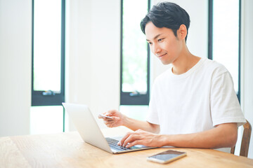 Fototapeta premium ノートパソコンでクレジットカード決済をする若い男性