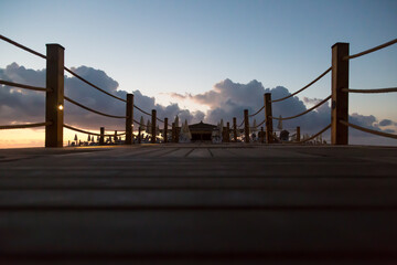Sunrise over wooden pier ocean.