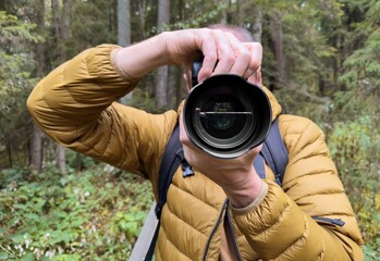 Fototapeta premium Man photographer taking photo in nature, view on lens