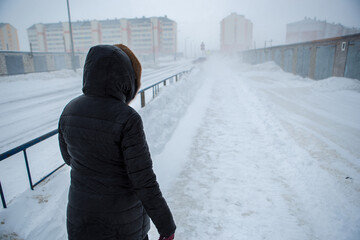 Winter is coming by severe blizzard. Poor visibility in heavy snow storm on path. Woman slowly and...