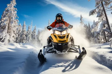 Fotobehang A man rides a snowmobile against the backdrop of beautiful snow-covered fir trees on a sunny day, winter active recreation on snowmobiles © Iaroslava