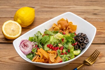 a colorful vegetable salad and chips on a wooden table with a yellow fork