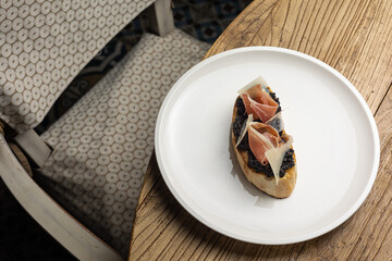 Tasty bruschetta with jamon and cheese on a wooden table