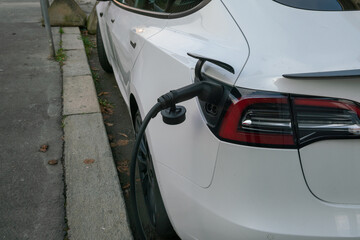 Fototapeta premium electric car charging, plug in to draw energy in the dedicated car park. Zero emissions in cities with green ecological policies. bonuses