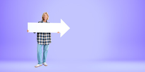 Young woman standing with blank mock up arrow board, empty bright background