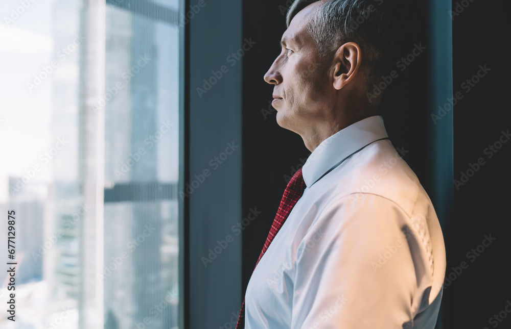 Sticker Serious businessman standing near window