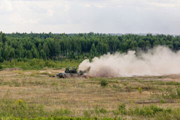Heavy combat vehicles tanks drive around the butts and put up a smoke screen