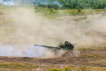 Obraz na płótnie Canvas Heavy combat vehicles tanks drive around the butts and put up a smoke screen