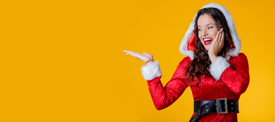 young woman wearing santa claus costume isolated pointing