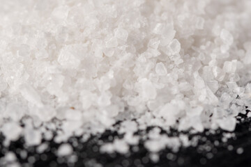 A heap of white salt crystals on a black stone background