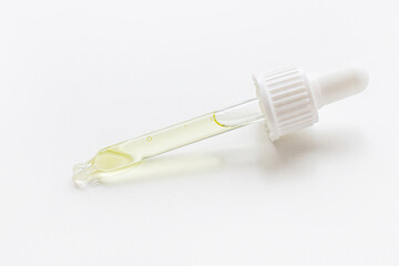 Pipette with golden serum or gel or serum, yellow on a light background.