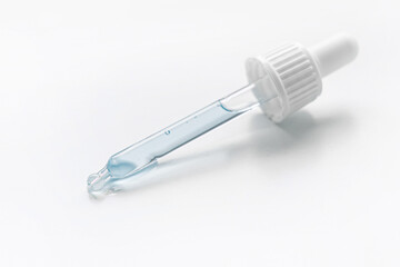 Cosmetic pipette with blue and blue gel, serum, serum on a light background.