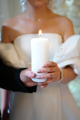 The bride and groom hold a burning candle in their hands as a symbol of the family hearth. Wedding ceremony.
