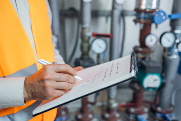Engineer checking operating Industrial Chillers, hot water pump and pipe line for make high temperature condition in HVAC systems.