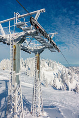 Fototapeta premium Schneebedeckter Skiliftmast an einem sonnigen Wintertag