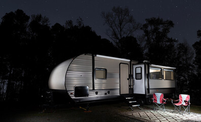 Stars in the sky above an RV with a forest silhouetted behind. 