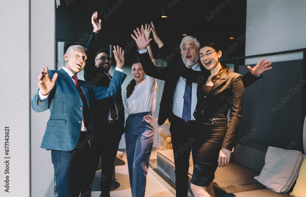 Poster Group of diverse colleagues giving high five while standing in office