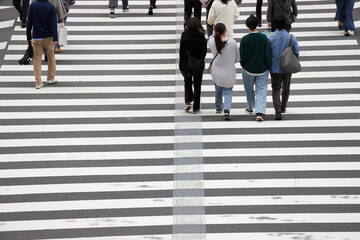 都市の交差点の横断歩道を渡る人々の姿