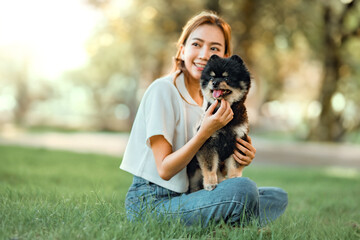 Happy asian woman playing with dog together in park outdoors, summer vacation.