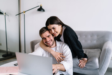 Happy couple browsing internet on laptop at home
