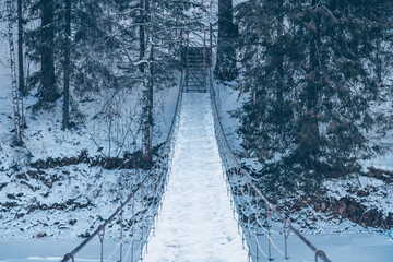 Beautiful rope hanging wooden bridge over the river. winter landscape