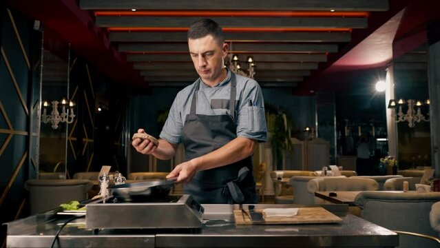 chef puts a beef cutlet on a pan for a burger in a professional kitchen of an Italian restaurant