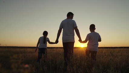 Family, dad, daughter, son go hand in hand outdoors in summer, Silhouette. Parental care for children. Happy family, group of people, nature. Dad with children, boy, girl walks through field at sunset