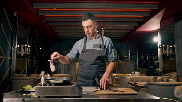  chef grilling beef patty with garlic and rosemary for burger in professional kitchen of Italian restaurant