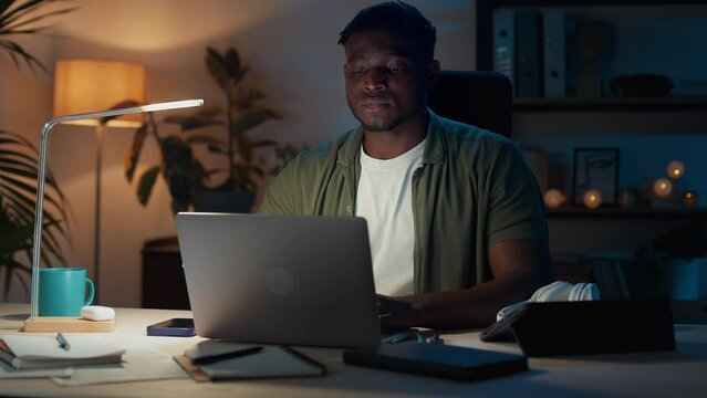Pensive freelancer using laptop for evening work at home