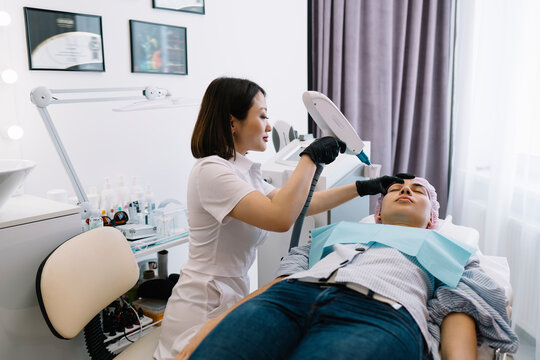 Professional cosmetologist doing facial photo epilation on client