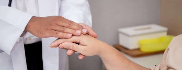 Fototapeta na wymiar Closeup hands of doctor man encourage with elderly patient at the hospital, physician take care and holding hands for consoling senior sick, diagnostic disease and illness, medical concept.