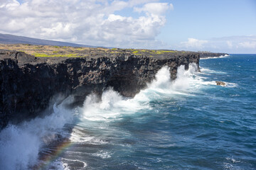 Blue waves crash on the steep coast and create rainbows, Chain of Craters Rd, Big Island
