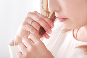 カラーリングした髪の毛を気にする若い女性