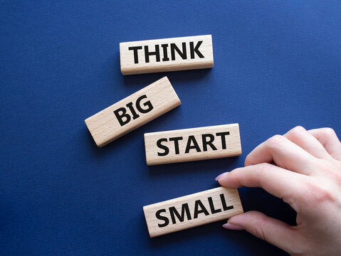 Think big start small symbol. Concept words Think big start small on wooden blocks. Beautiful deep blue background. Businessman hand. Business and Think big start small concept. Copy space