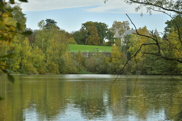 Le château en partie dissimulé derrière les arbres vu depuis l'un des étangs du domaine du château de la Hulpe 