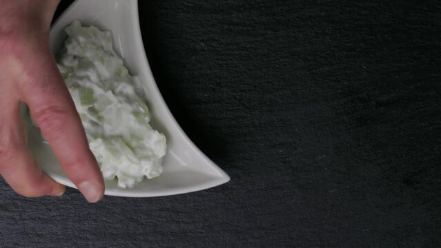 Triangle-shaped plates featuring the Bulgarian appetizer Snezhanka and the traditional Balkan version of Olivier salad called Ruska Salata, garnished with a small banana pepper an olive