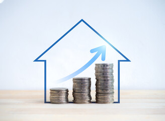 Upward arrow on money coin stack as growth graph steps in blue home shape symbol on wood desk and...
