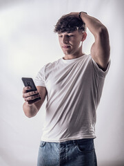 A man holding a cell phone in his hand, disappointed or sad at what he sees. Handsome Young Man Captivated by His Cell Phone