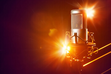 Professional microphone on the stage with orange light beams. Live music, concert or entertainment.