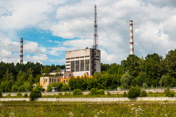 Fototapeta na wymiar Buildings on the territory of the Obninsk nuclear power plant towering above the trees. Mixing industrial and natural landscape