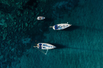 Sailing yachts anchored in blue sea, top view. Sailing yacht on dark background, aerial view.