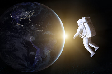 Fototapeta na wymiar Astronaut in deep space looks on night Earth planet. Elements of this image furnished by NASA.