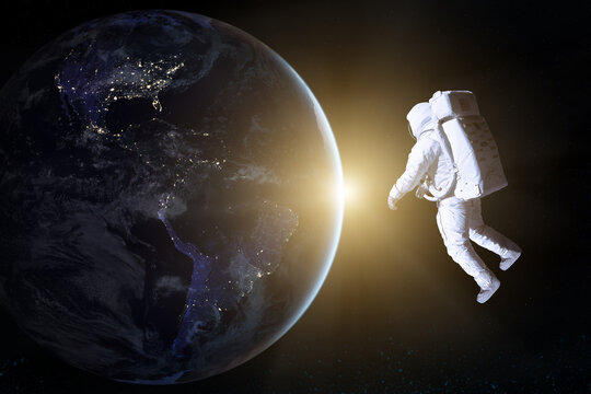 Astronaut in deep space looks on night Earth planet. Elements of this image furnished by NASA.